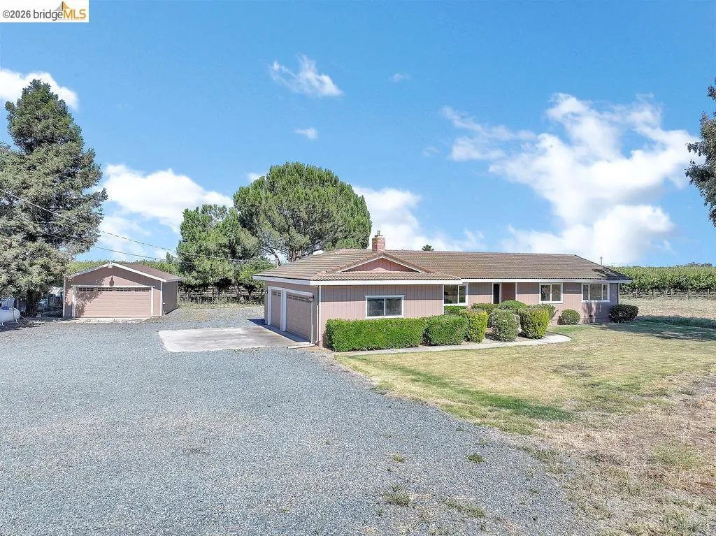 Ranch-style residence featuring a gravel driveway, two-car attached garage, and a separate single-car garage structure