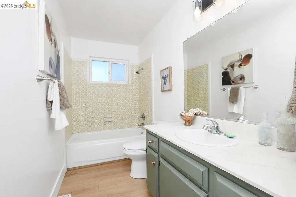 Bathroom featuring a white bathtub, wood-finish flooring, and a window above the tub