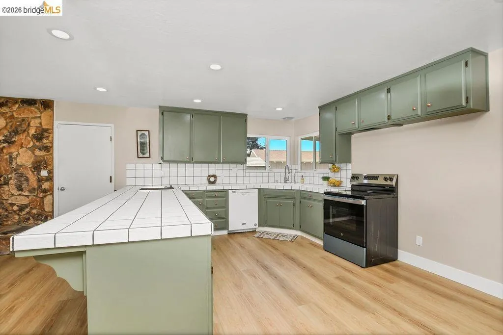 Kitchen featuring light wood-finish flooring, recessed lighting, and a stone-clad accent wall