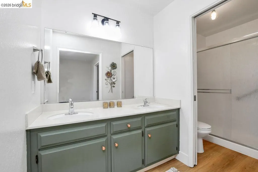 Dual sink vanity with sage green cabinetry and white countertops