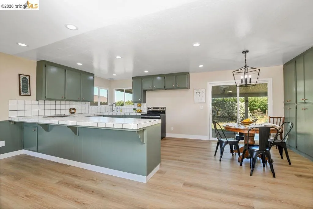 Open-concept kitchen and dining area featuring wood-finish flooring, recessed lighting, and a sliding glass door