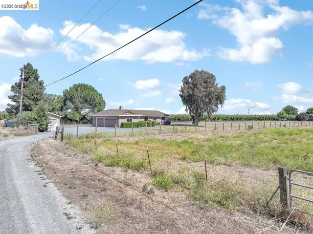 Ranch-style residence featuring a two-car garage, brick chimney, and a gravel driveway