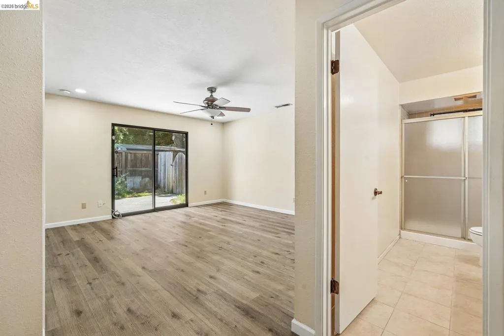 Spacious room featuring wood-finish flooring, a ceiling fan, and recessed lighting