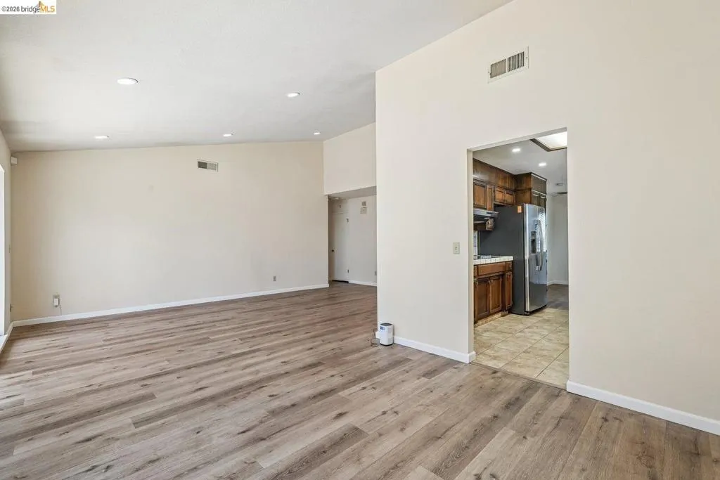 Spacious living area featuring wood-finish flooring, recessed lighting, and vaulted ceilings