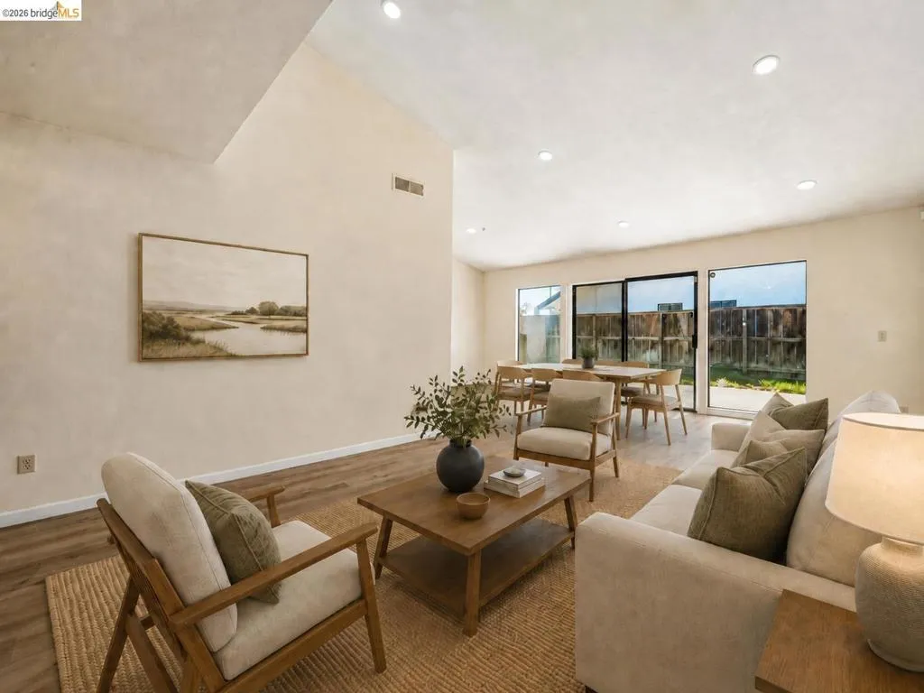 Vaulted ceiling, recessed lighting, wood-finish flooring, sliding glass doors, and a neutral color palette
