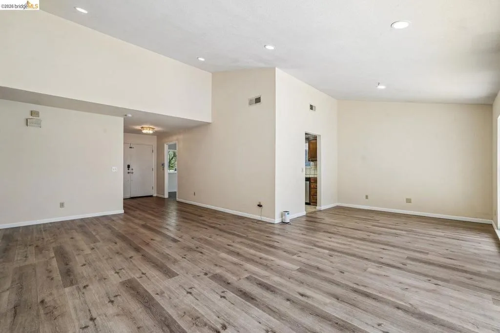 Spacious living area featuring wood-finish flooring, recessed lighting, and vaulted ceilings