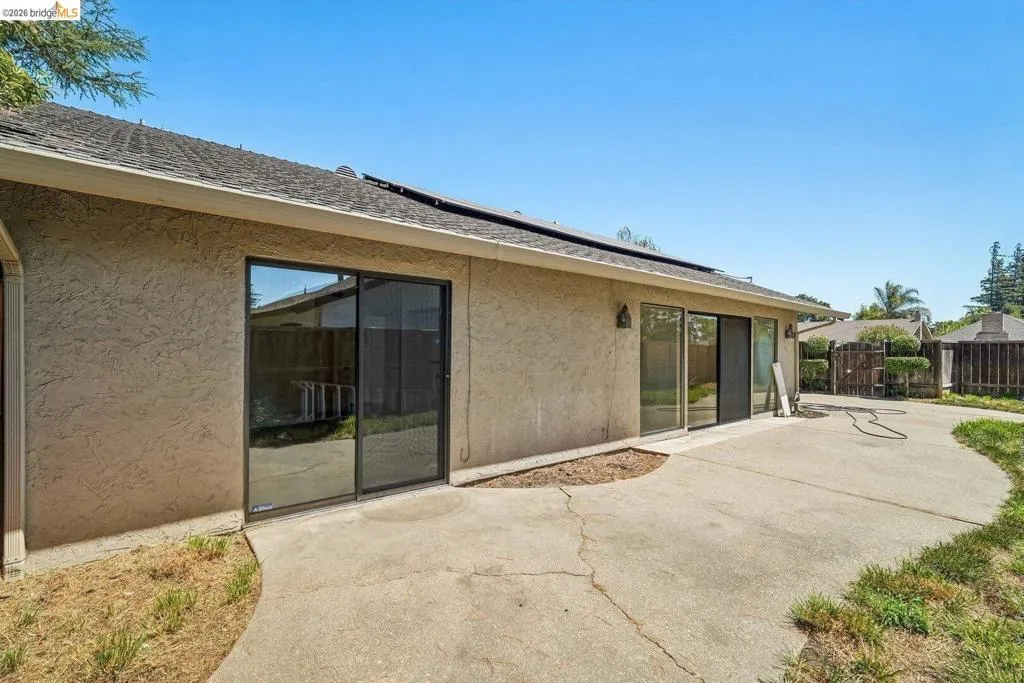 Rear exterior featuring stucco finish, multiple sliding glass doors, and solar panels on the roof