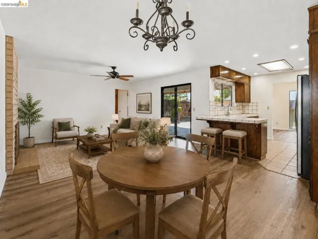 Wood-finish flooring throughout, brick fireplace, and ceiling fan