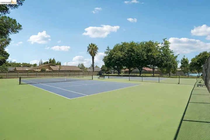 Expansive tennis courts featuring blue and green hard surfaces, surrounded by chain-link fencing