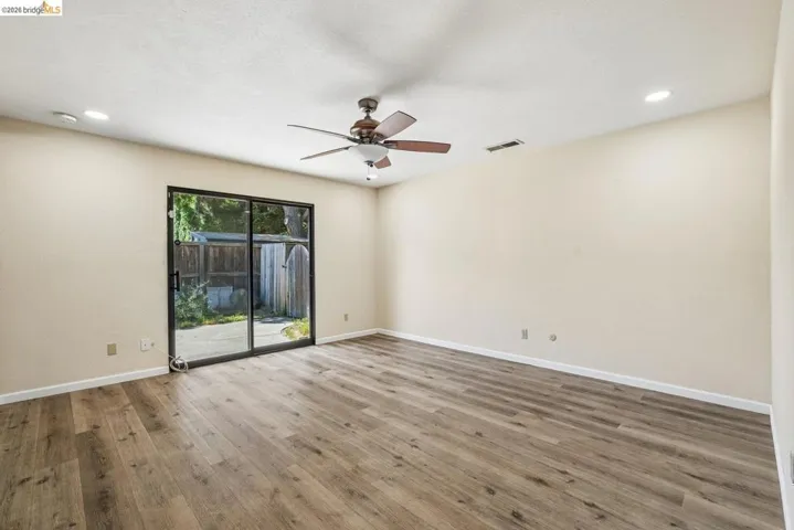 Spacious room featuring wood-finish flooring, a contemporary ceiling fan, recessed lighting, and a glass sliding door providing access to the outdoor area