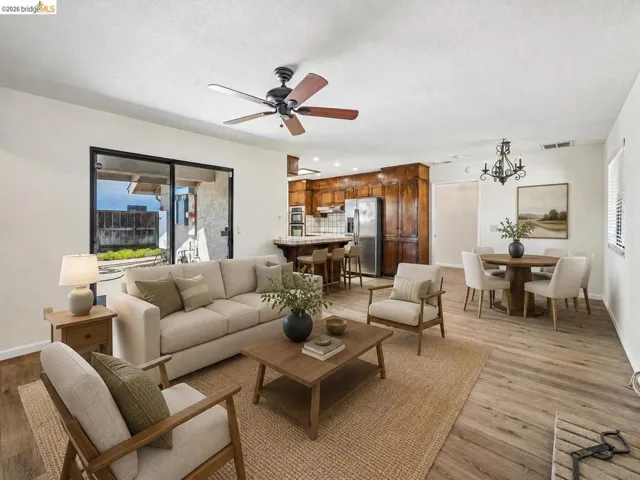 Wood-finish flooring throughout, with a ceiling fan in the living area, and a dining area featuring a chandelier