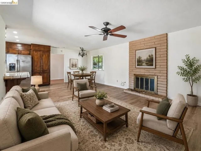 Brick fireplace with a brass firebox, wood-finish flooring, recessed lighting, and a ceiling fan