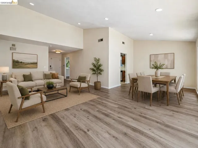 Open-concept living and dining areas featuring vaulted ceilings, recessed lighting, and wood-finish flooring