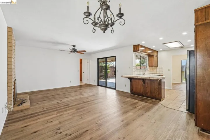Open-concept living space featuring wood-finish flooring, a brick fireplace, and direct patio access