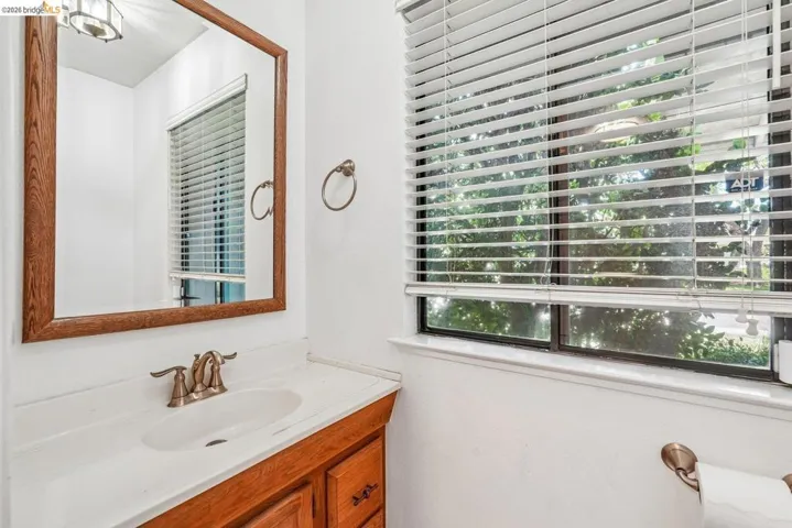 Bathroom featuring a wood-finish vanity with a white countertop and an integrated sink