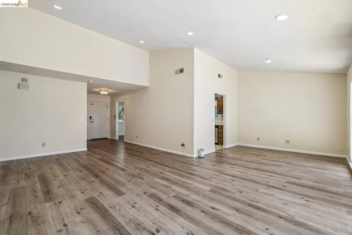 Spacious living area featuring wood-finish flooring, recessed lighting, and vaulted ceilings