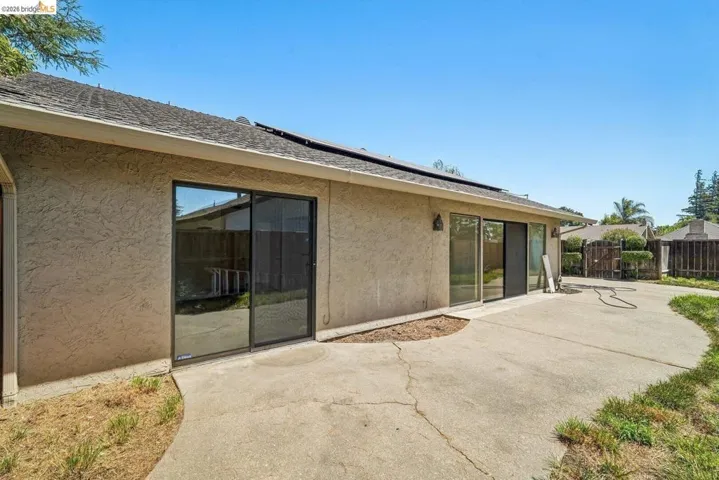 Rear exterior featuring stucco finish, multiple sliding glass doors, and solar panels on the roof
