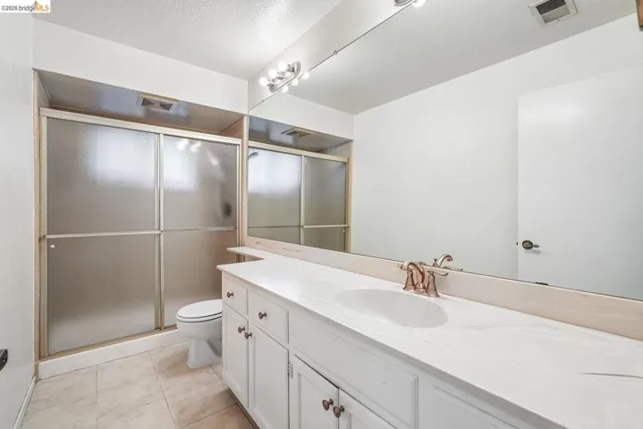 Bathroom featuring a spacious vanity with an integrated sink, polished countertop, and a wall-mounted mirror