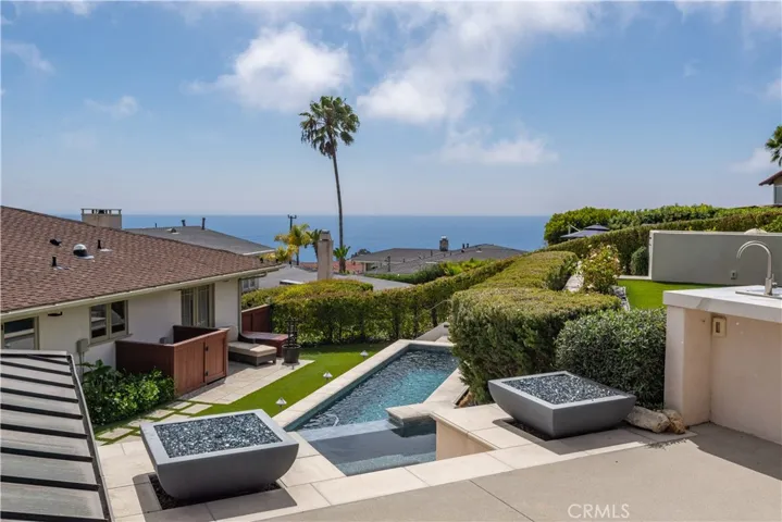 Resort like backyard with cabana, kitchen, pool with wall fall, spa, and 2 gathering areas.