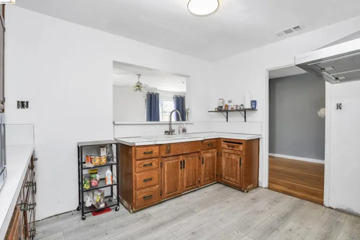 Kitchen featuring wood cabinetry, light-toned countertops, and light wood-finish flooring