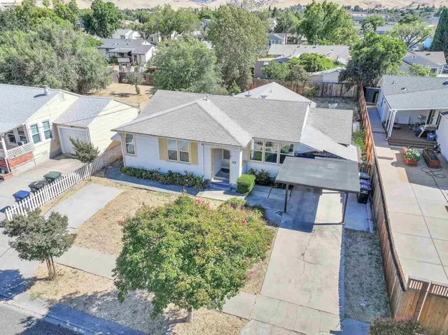 Single-story residence featuring a carport, front yard with mature tree, and a concrete driveway