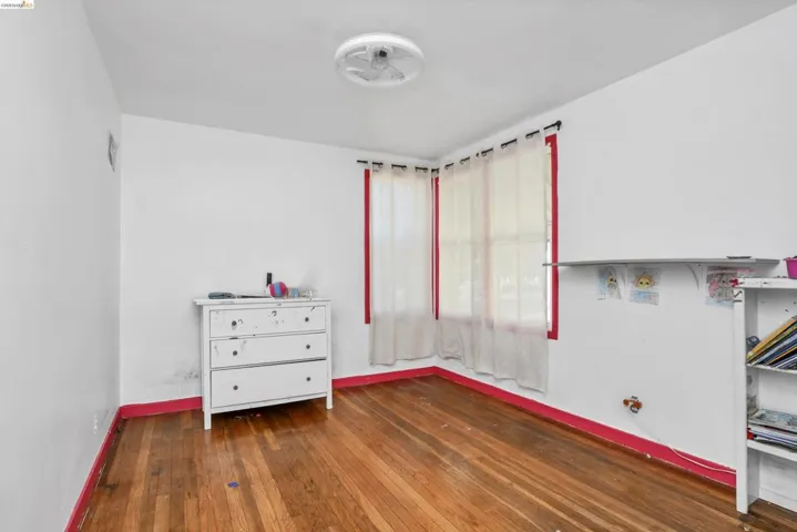 Hardwood flooring, two windows with red trim, and a ceiling-mounted light fixture