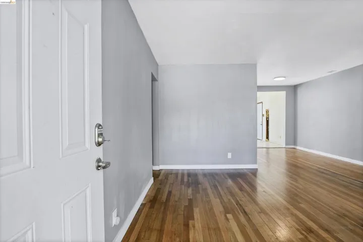 Entryway featuring a white paneled door with brushed nickel hardware, light gray walls, white baseboards, and wood-finish flooring
