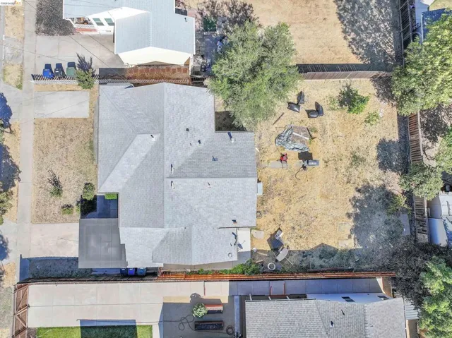 Property featuring a light gray shingle roof, concrete driveway, and a fenced backyard with mature trees