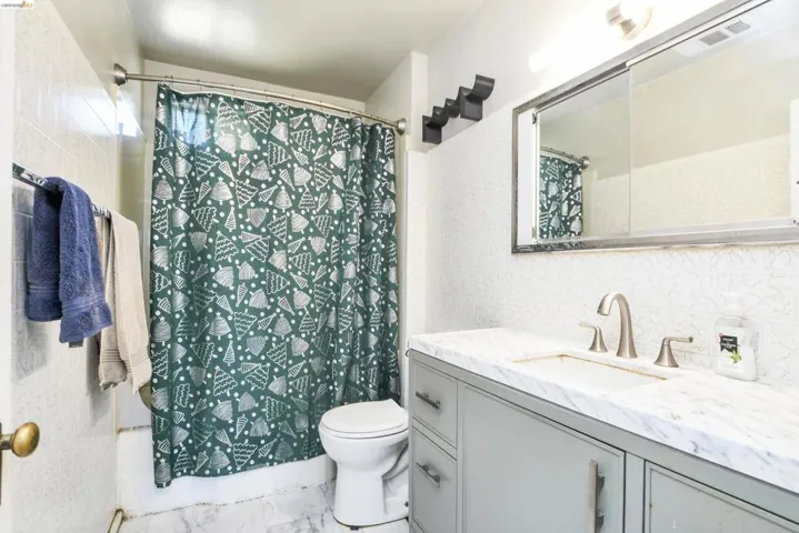 Bathroom featuring a vanity with a white stone-finish countertop, brushed nickel faucet, and a large mirrored medicine cabinet