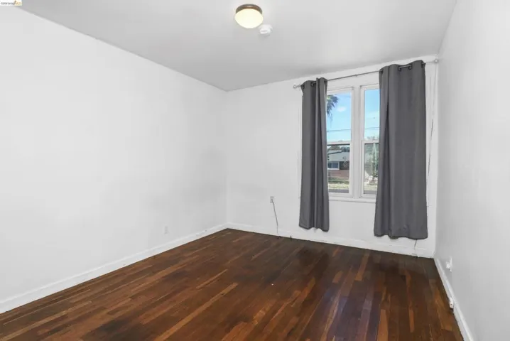 Room featuring dark wood-finish flooring, white walls, and a ceiling-mounted light fixture