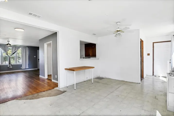 Open concept living area featuring wood-finish flooring in the foreground and a pass-through window to the adjacent space