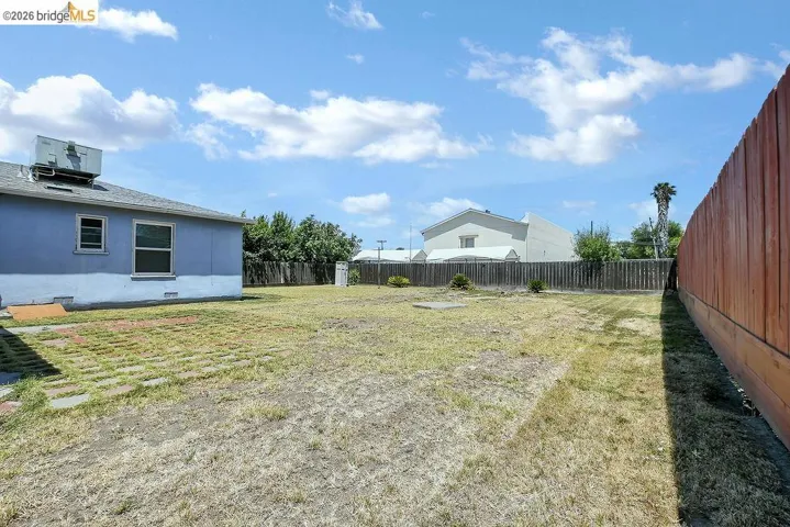 Spacious backyard featuring a wood fence, concrete patio pavers, and a large open area