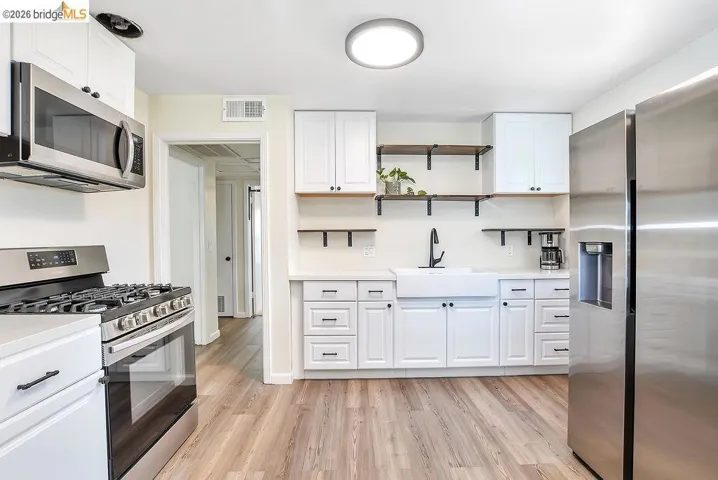 Bright kitchen with white cabinetry and vinyl flooring