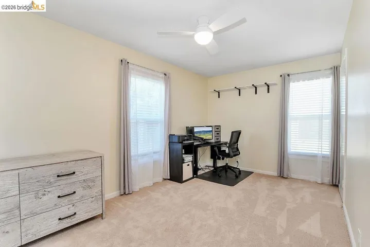 Carpeted room with light-toned walls and two windows fitted with blinds