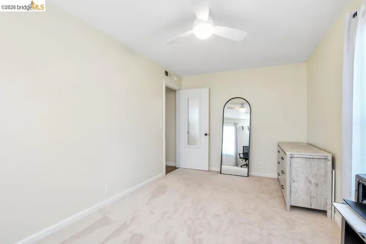 Carpeted room with a ceiling fan light fixture, white walls, and white trim
