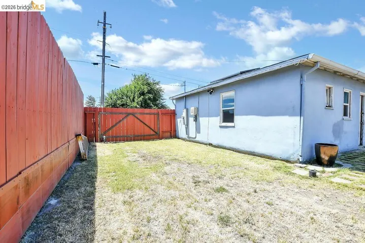 Private backyard space featuring a red wooden perimeter fence and a corresponding gate