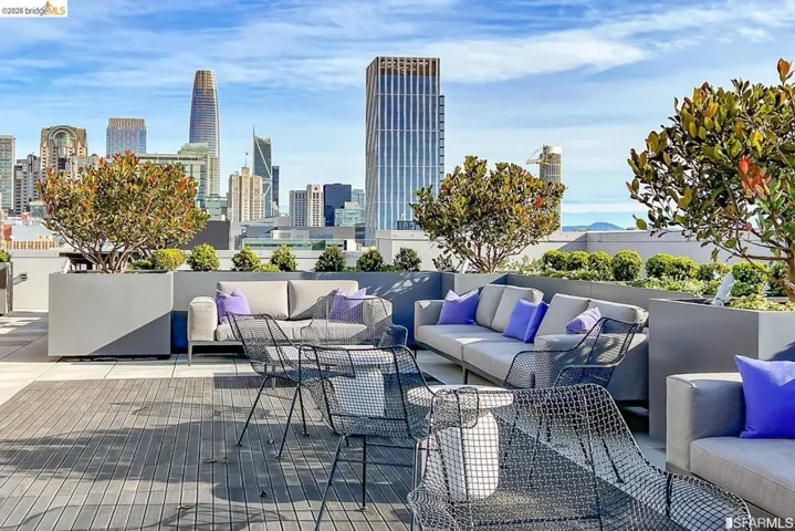 Rooftop terrace featuring composite decking, integrated planters with mature trees, and a cityscape backdrop
