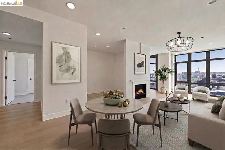Open-concept living area featuring a fireplace with a white mantel, floor-to-ceiling windows, recessed lighting, wood-finish flooring, and a modern ceiling fixture