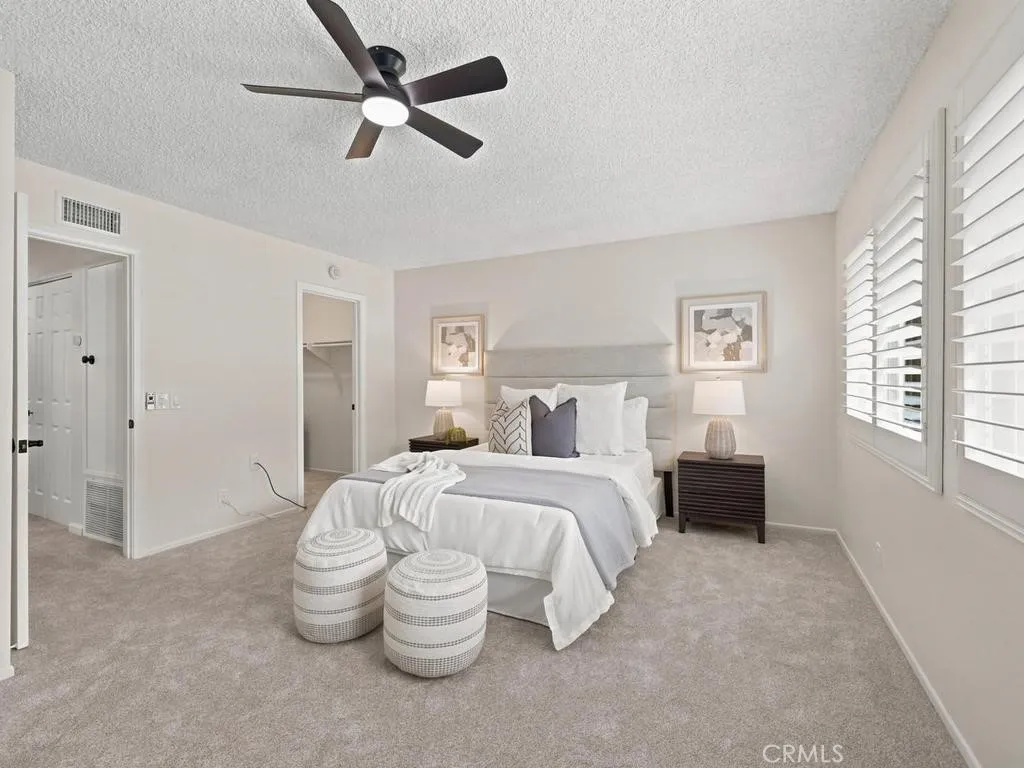 Primary bedroom, newer windows with split plantation shutters. New carpet and ceiling fan with walk-in closet