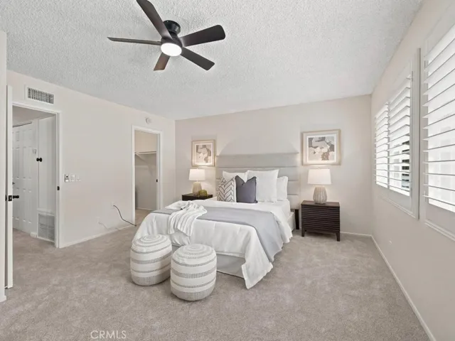Primary bedroom, newer windows with split plantation shutters. New carpet and ceiling fan with walk-in closet