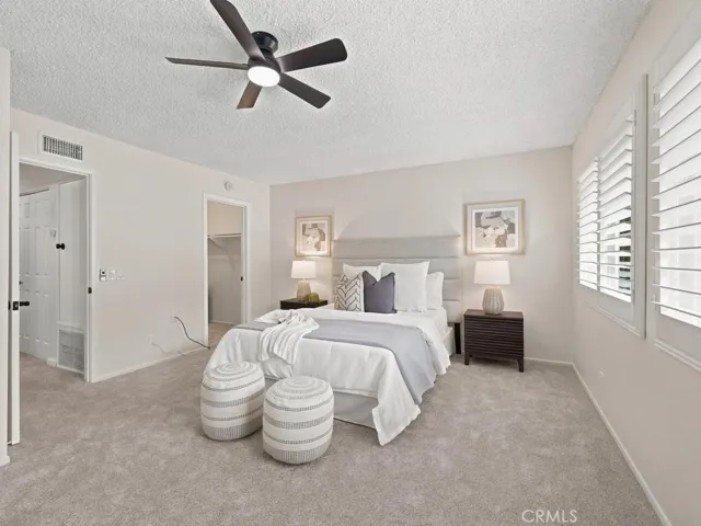 Primary bedroom, newer windows with split plantation shutters. New carpet and ceiling fan with walk-in closet