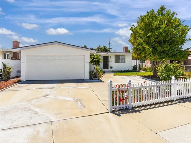 Beautifully landscaped with mature fruit trees, diverse plants and flowers, a charming white picket fence, and a two-car garage with a driveway for convenient additional parking.