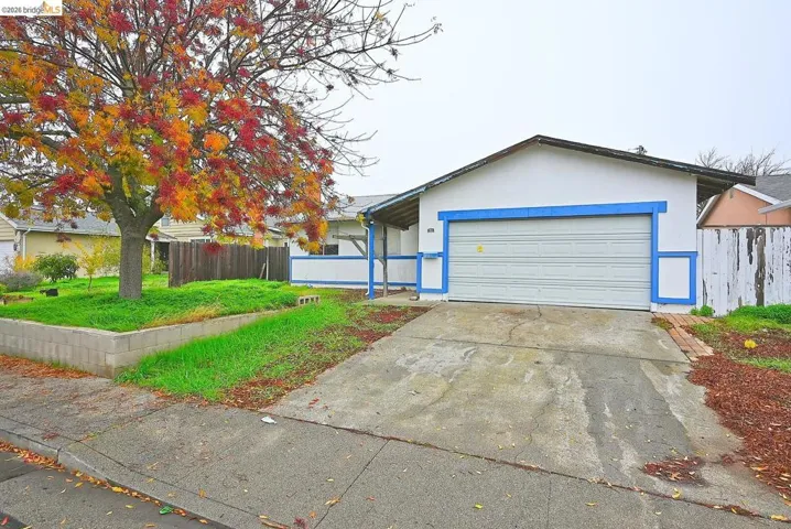 Single-story residence featuring a white stucco exterior with blue trim accents and an attached garage