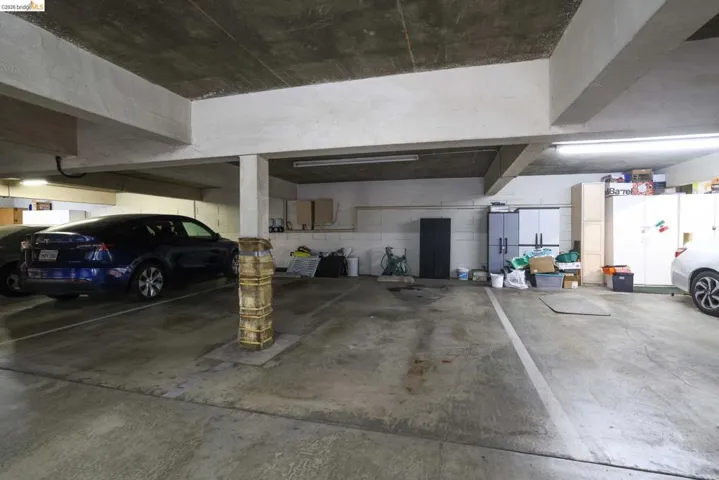Concrete parking area featuring overhead lighting and visible structural beams