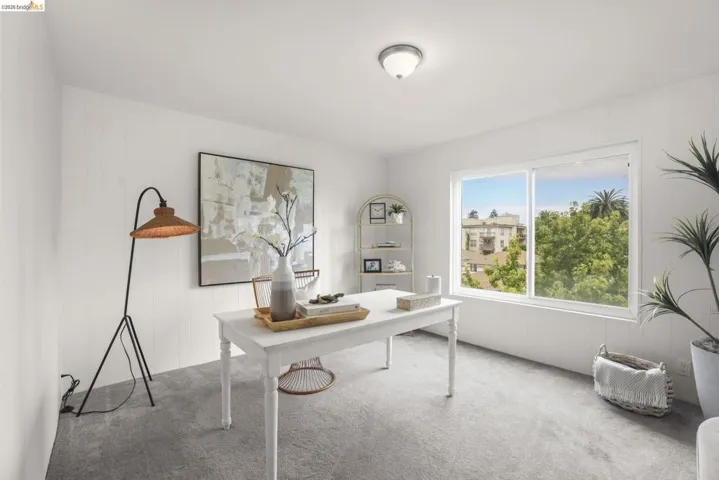 Bright room featuring a large window, paneling on walls, gray carpet flooring, and a flush-mount ceiling light fixture