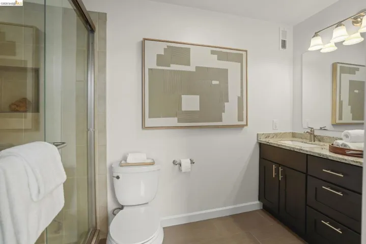 Bathroom featuring a glass-enclosed shower, dark wood vanity with a light-toned countertop, and tile flooring