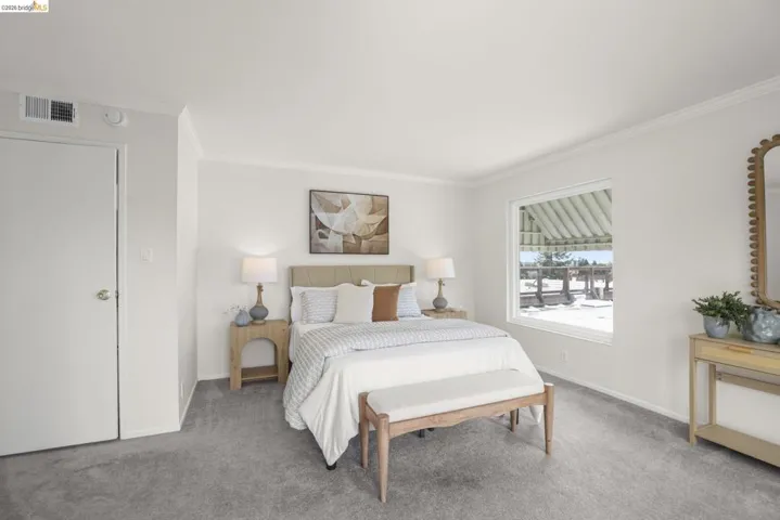 Bedroom with plush gray carpeting, white walls, and crown molding