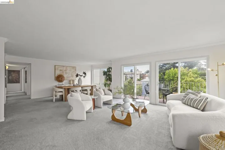Spacious living area featuring light-toned carpeting and white walls