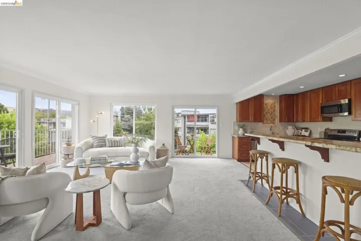 Open-concept living area with light-colored carpeting and white crown molding