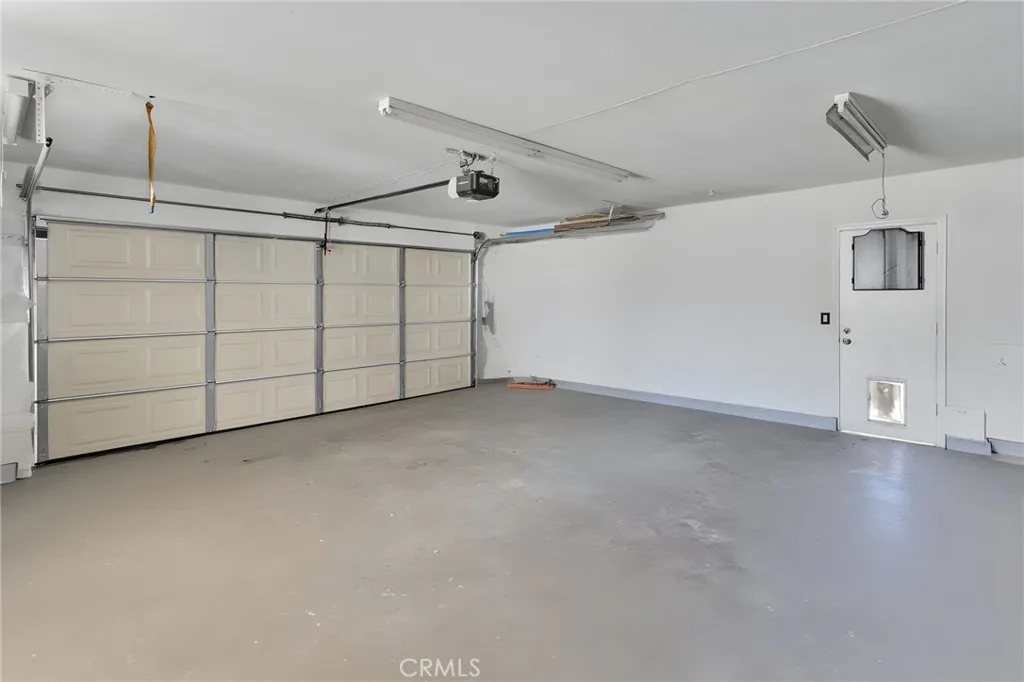 Alternate perspective of the clean garage interior showing the pristine concrete floor and a convenient side-yard pedestrian exit door.